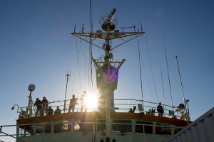 Scientists and crew gather on the bridge of the R/V Knorr as the ship passes through Prince Christian Sound, a channel through southern Greenland that connects the Labrador Sea with the Irminger Sea. The stunningly close views of mountains and icebergs were a rare treat for those taking part in the Overturning in the Sub-polar North Atlantic Program (O-SNAP) research cruise this summer. It was also one of the Knorr's last research cruises to the region. After 44 years in service to science, the ship will be de-commissioned next year and replaced by the R/V Neil Armstrong. (Photo by Carolina Nobre, Woods Hole Oceanographic Institution)