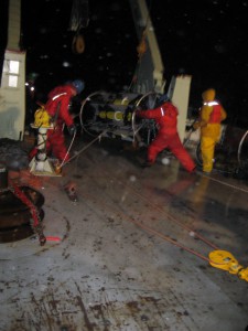 Getting the first of the two SALP frames into position. When both frames are perched at the stern's edge, the rew will hoist them over one by one. Four more hours and 2,250 more meters of mooring to go. (Photo by Donovan Hohn, Woods Hole Oceanographic Institution)